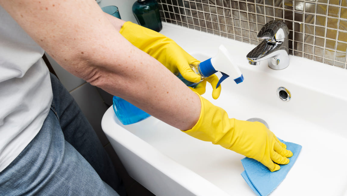 woman-with-rubber-gloves-cleaning-sink 1